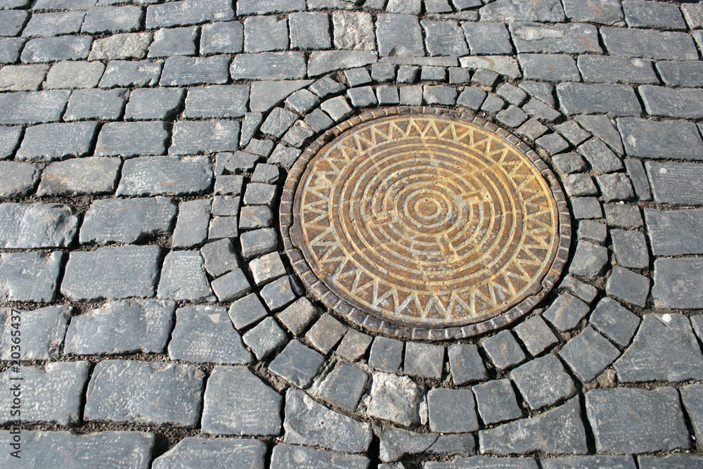 The pig-iron hatch on cobblestone pavement