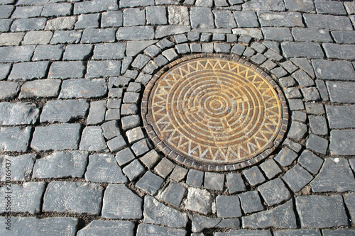 The pig-iron hatch on cobblestone pavement