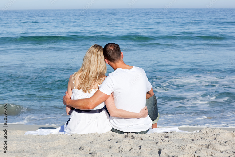 Affectionate couple sitting on the sand at the beach