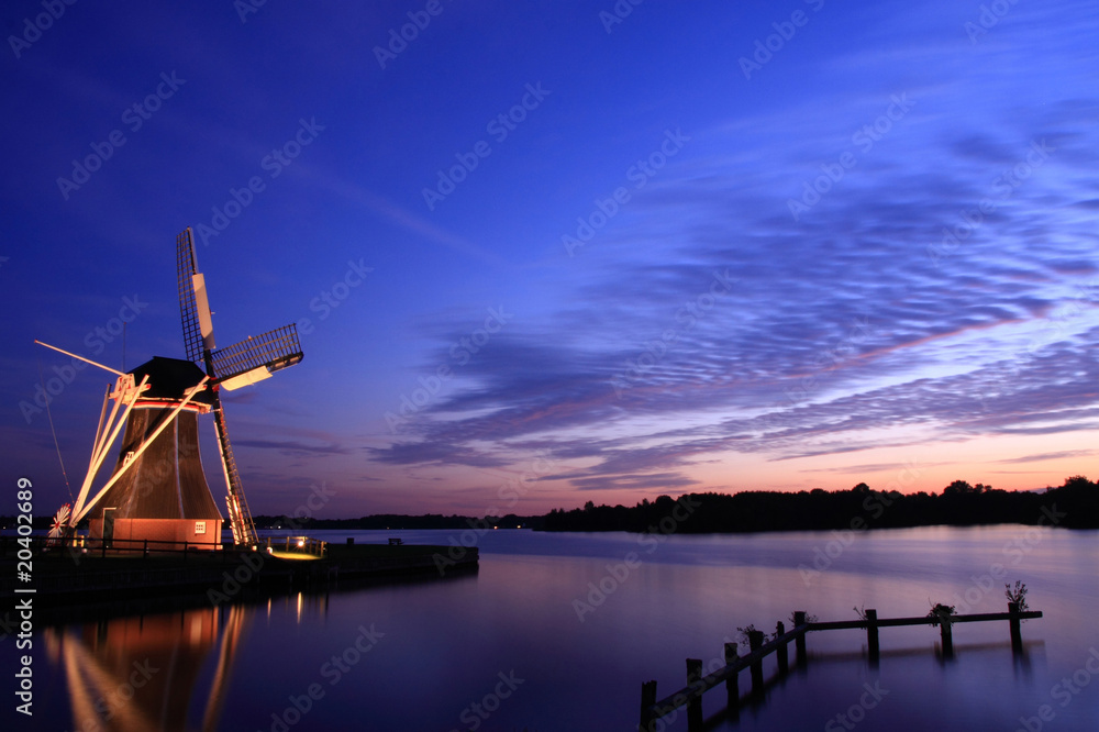 Dutch sunset with windmill at a lake.