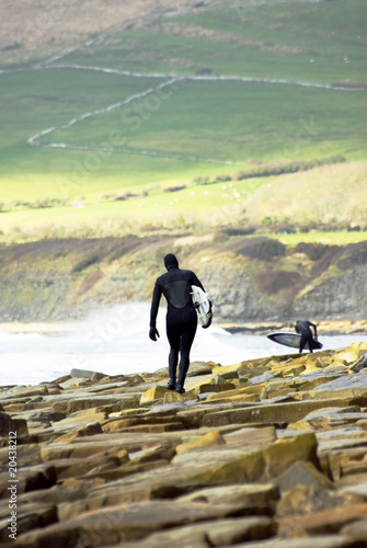 two male surfers standing on boulders at kimmeridge bay England photo