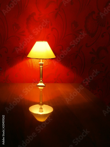 brass table lamp with reflection on shiny table and red floral w