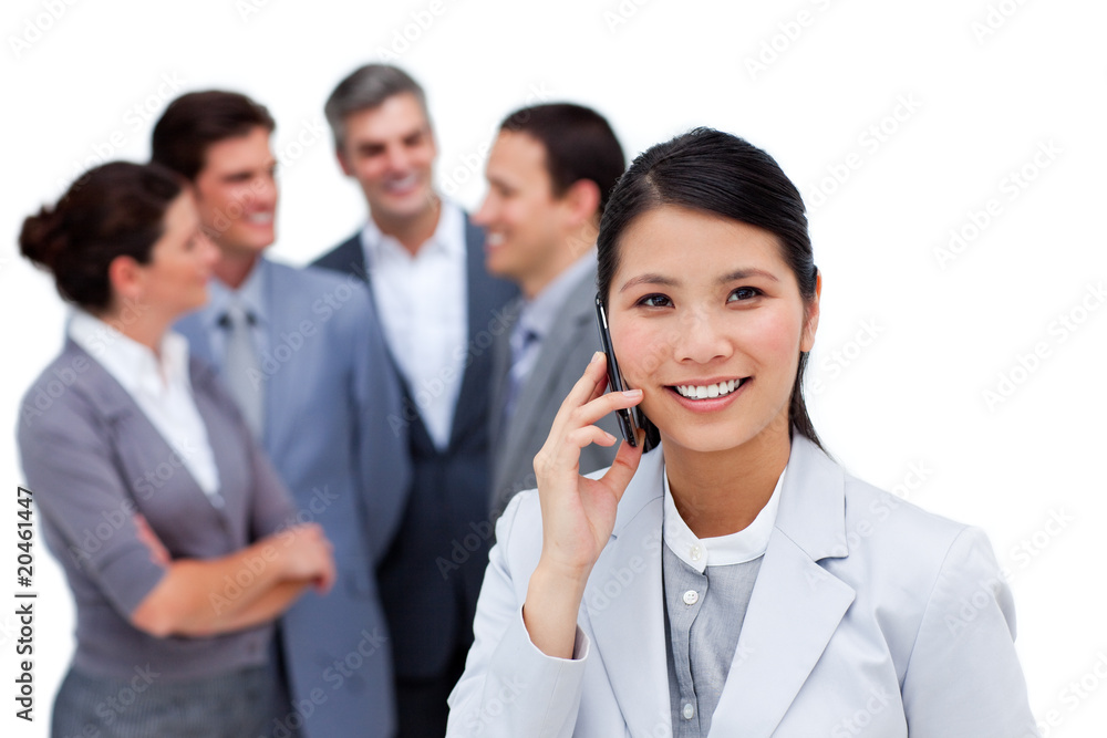 Jolly businesswoman talking on phone in front of her team Jolly businesswoman talking on phone in front of her team