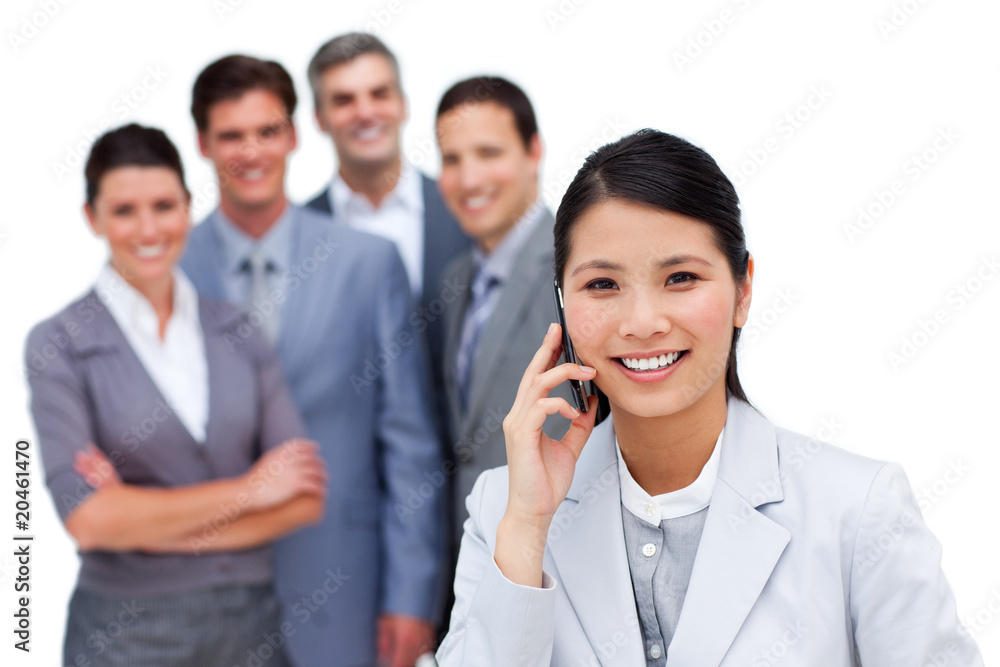 Asian woman talking on phone in front of her team Asian woman talking on phone in front of her team