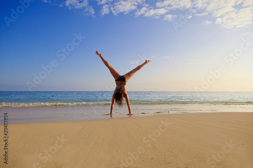 young woman doing a cartwheel on a hawaii beach