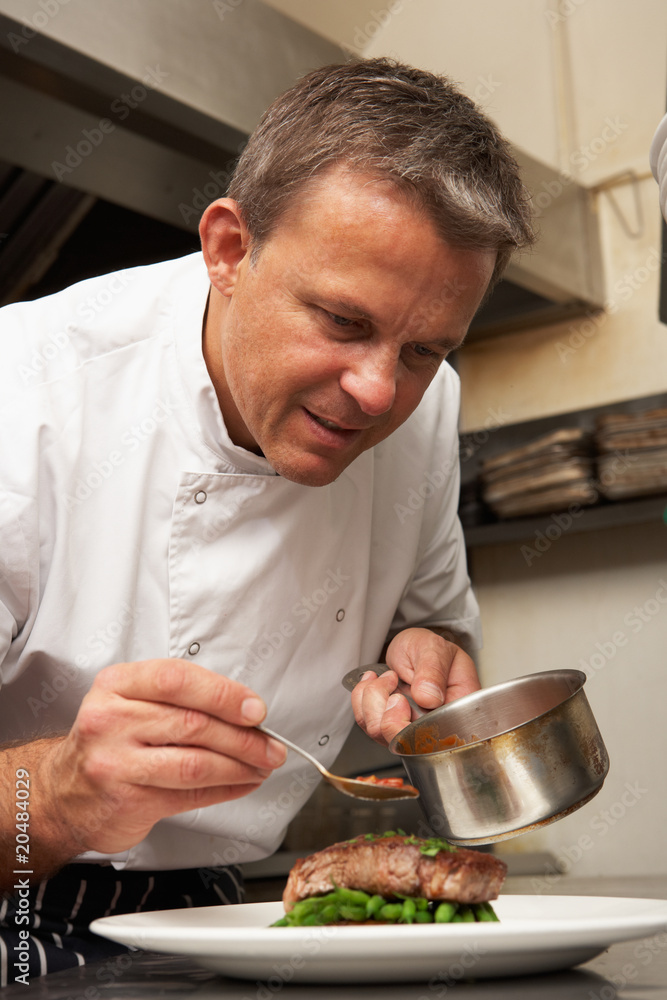 Chef Adding Sauce To Dish In Restaurant Kitchen Chef Adding Sauce To Dish In Restaurant Kitchen