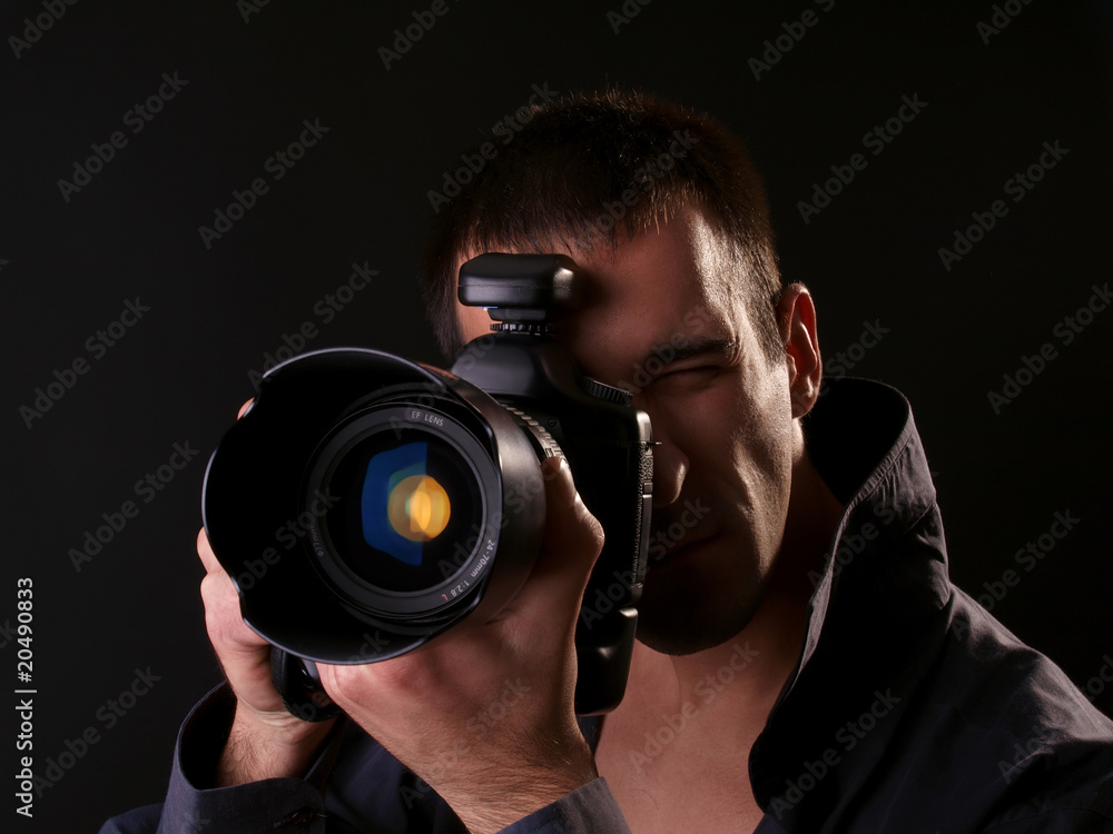 young male photographer trying out his new camera in studio young male photographer trying out his new camera in studio