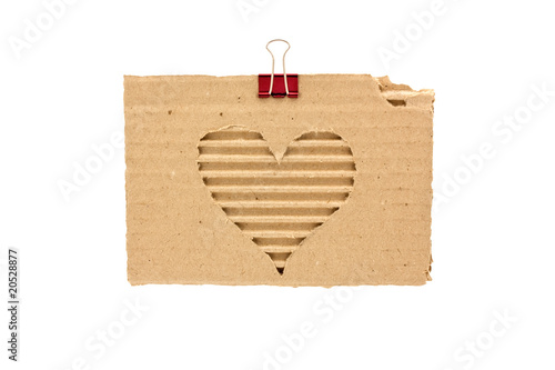 heart on a torn piece of cardboard with a metal clip for paper