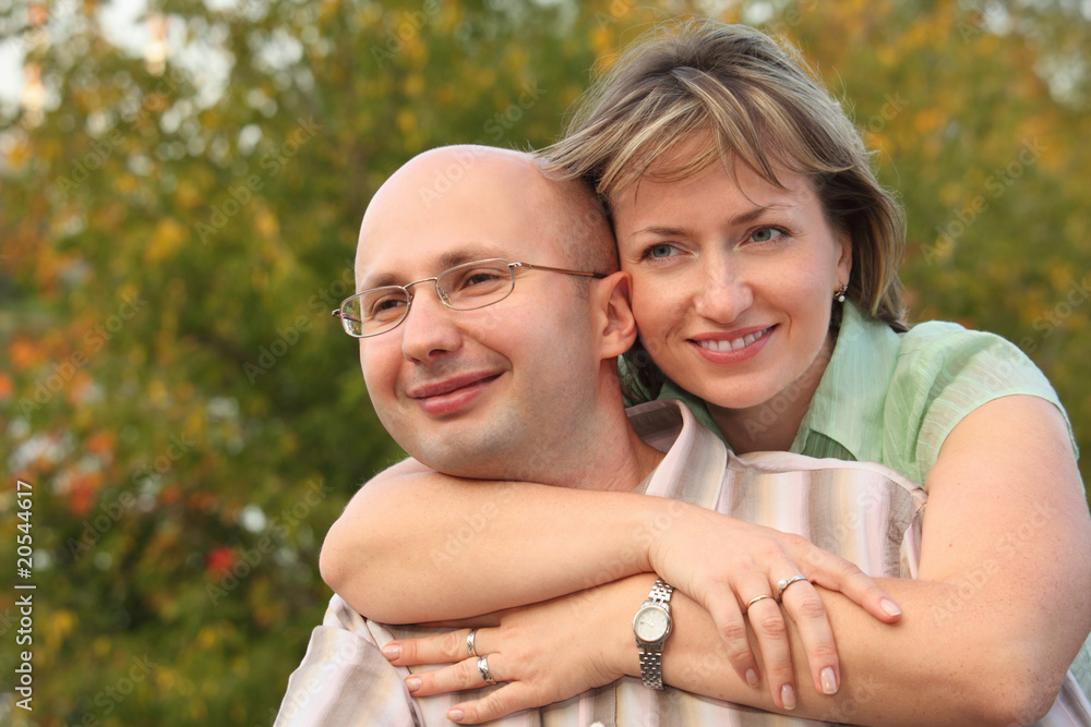 smiling man and woman in park. woman is embracing her man smiling man and woman in park. woman is embracing her man