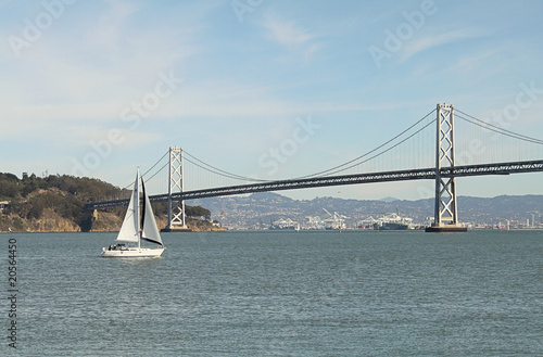 White sailboat with island and bridge as background