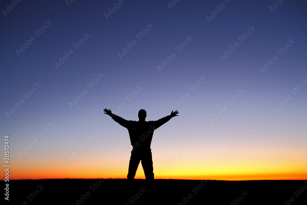 Silhouette of man with arms outstretched at sunset Silhouette of man with arms outstretched at sunset