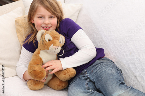 Little girl with toy tiger on sofa © ESLINE