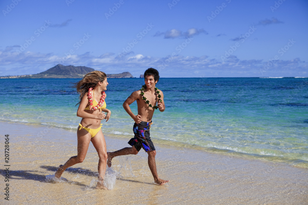 young couple running on the beach in hawaii