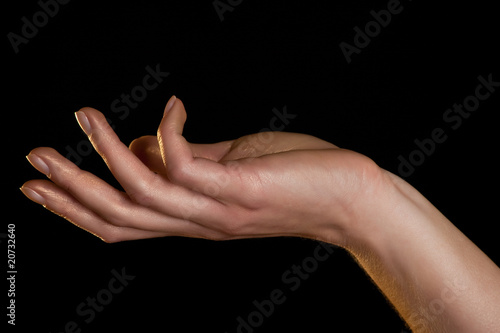 Female hand in golden light on a black