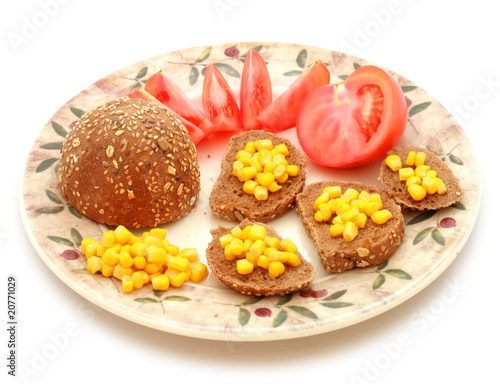 Whole-meal roll with corn and tomato on the plate
