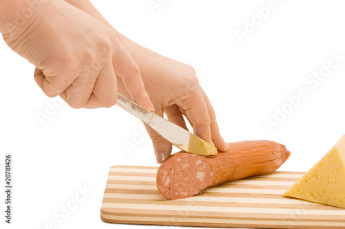 The hand with a knife cuts sausage