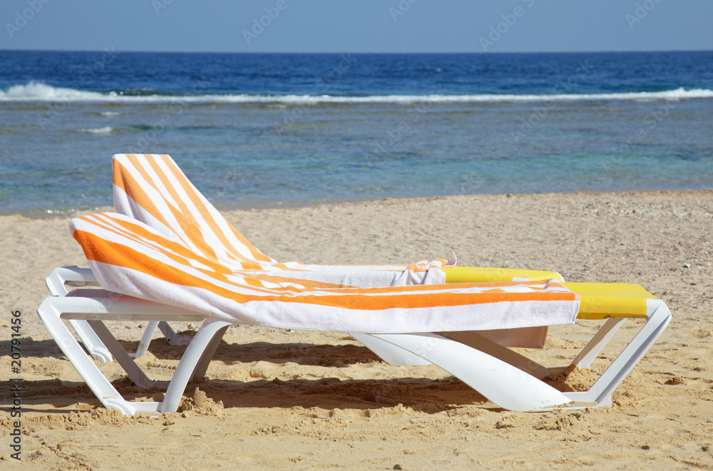 two chaise-longues with towels on beach two chaise-longues with towels on beach