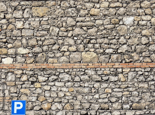 muro di pietre con cartello di parcheggio photo