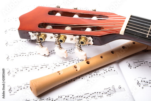 Guitar and wooden flute on sheet music. Close up.