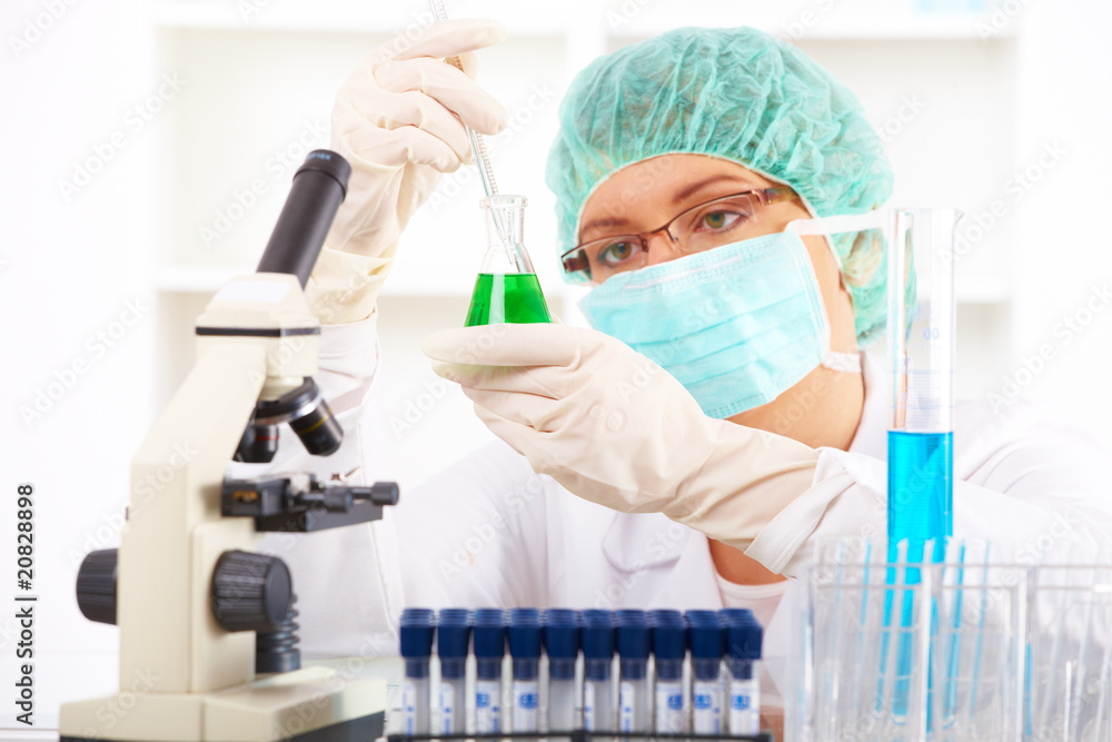 Female researcher holding up a test tube and retort Female researcher holding up a test tube and retort