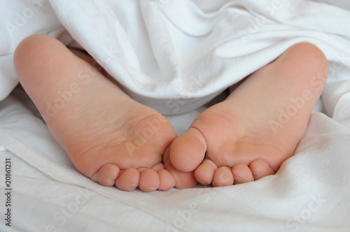 Kinderfüsse unter Bettlaken
