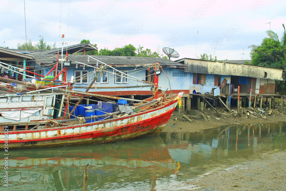 Fishermen's huts and old fishing boat in South of Thailand