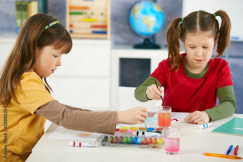 Naklejka premium Elementary age children painting in classroom