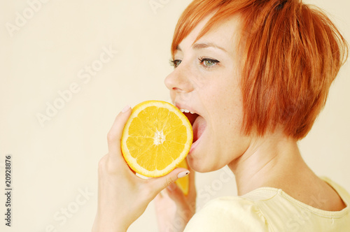 Young woman biting a slice of orange
