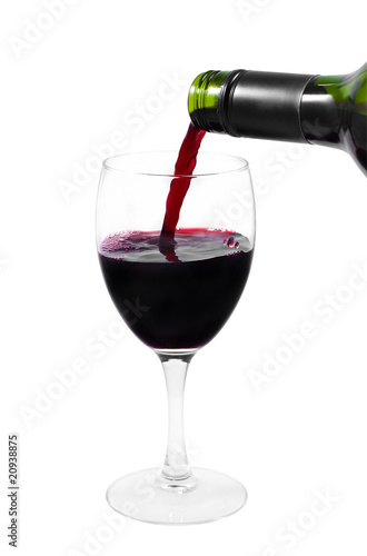 A bottle pouring red wine into a clear glass isolated on white