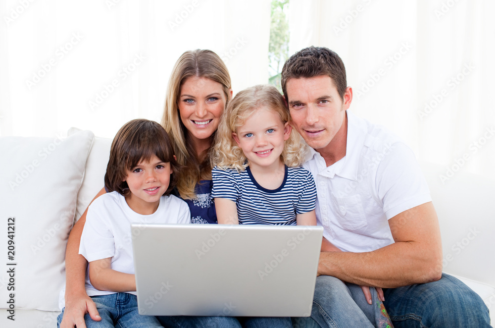 Portrait of a joyful family using a laptop sitting on sofa Portrait of a joyful family using a laptop sitting on sofa