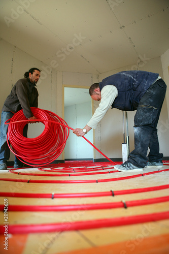 Hommes posant des tubes pour parquet chauffant photo