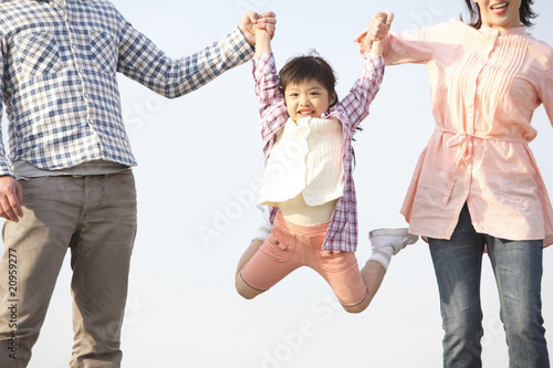 両親に手を引かれてジャンプする女の子