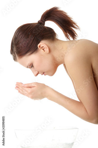 Beautiful young woman with hands in water