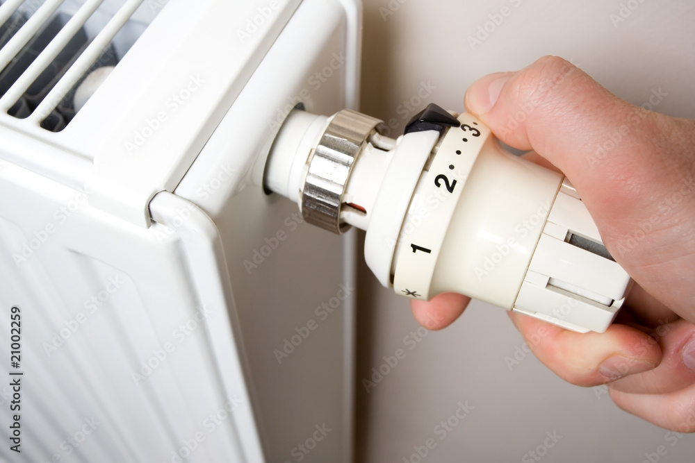 Radiator adjustment closeup. Men's hand adjusting radiator tem Radiator adjustment closeup. Men's hand adjusting radiator tem