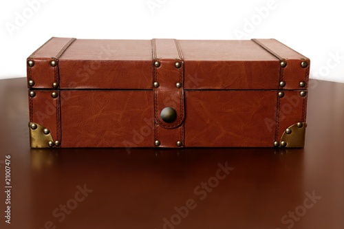 Brown leather suitcase over warm wood