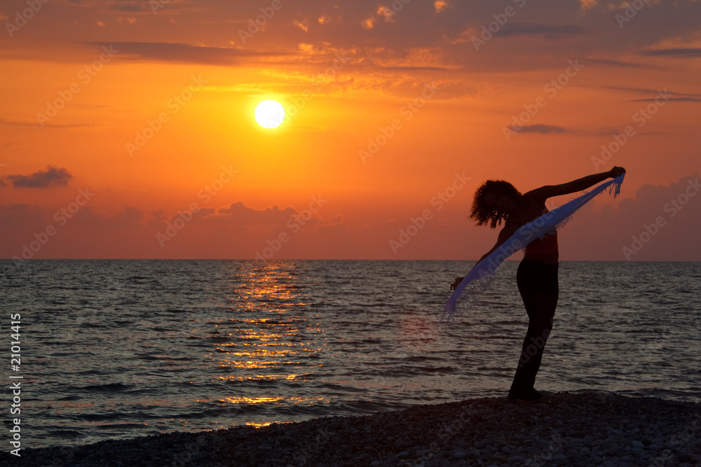 Silhouette of girl with handkerchief in hands at sunset.