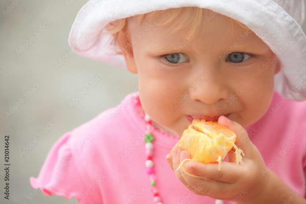 little girl is eating orange. focus on orange in hand. little girl is eating orange. focus on orange in hand.