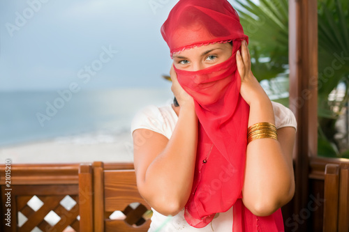 young woman in yashmak sitting  in an arbour on seacoast