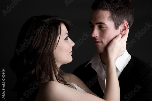 Young Couple Embracing against Dark Background