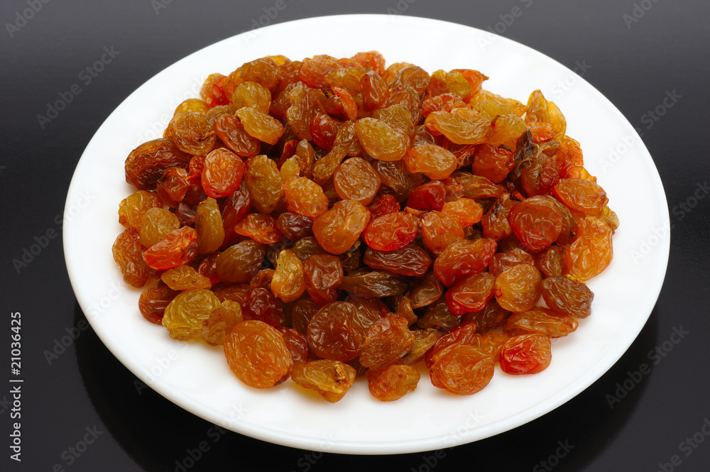 Raisin on a white plate on a black background Raisin on a white plate on a black background