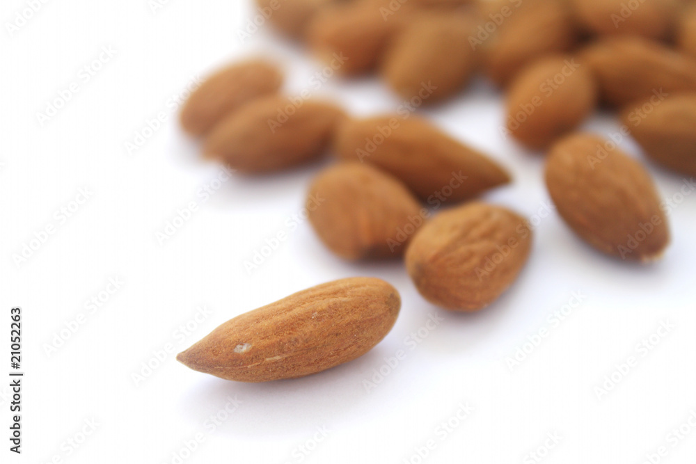 Group of almonds with single one in focus on white background Group of almonds with single one in focus on white background