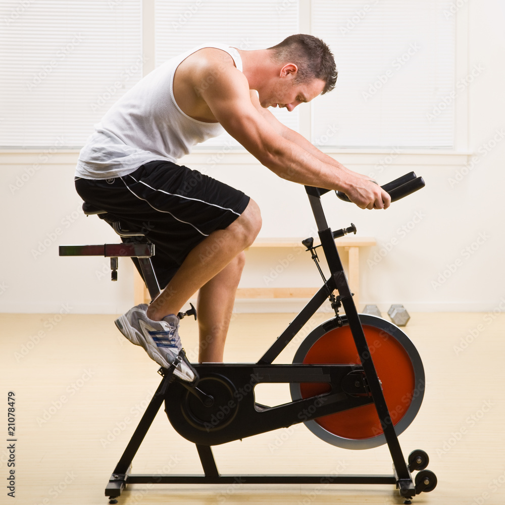 Man riding stationary bicycle in health club Man riding stationary bicycle in health club