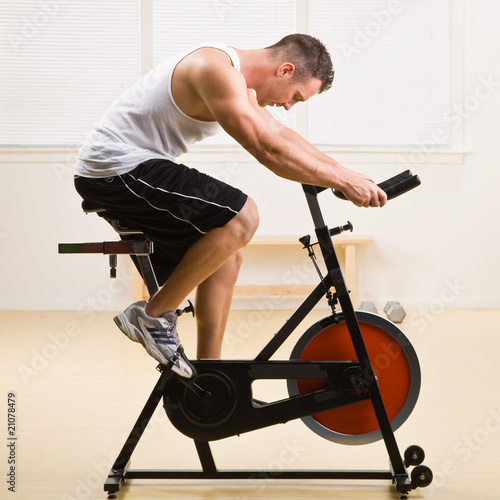 Man riding stationary bicycle in health club © AVAVA