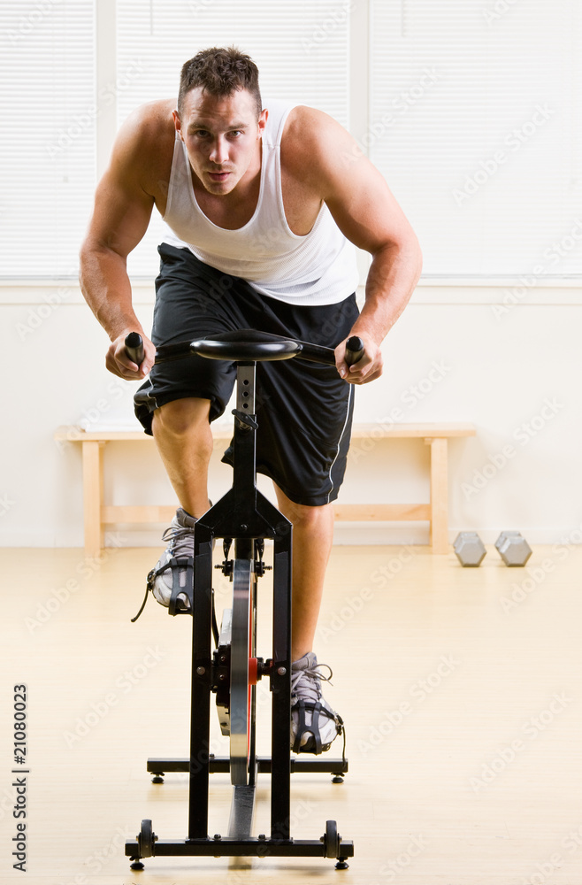 Fototapeta premium Man riding stationary bicycle in health club