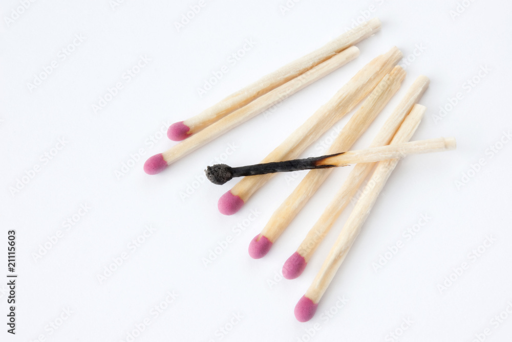 Close up of lined up matches with a burned one in the middle