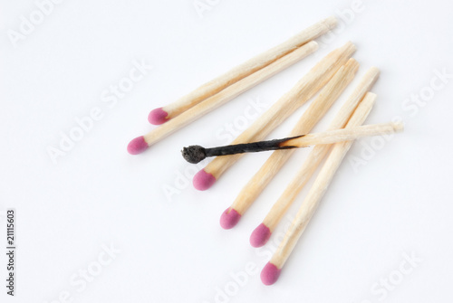 Close up of lined up matches with a burned one in the middle