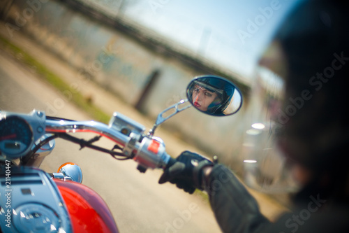 The young girl a motorcycle looks in a rear-view mirror