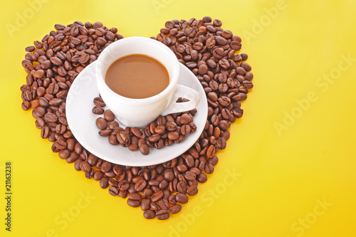 Small white cup of coffee with coffee grain on yellow background