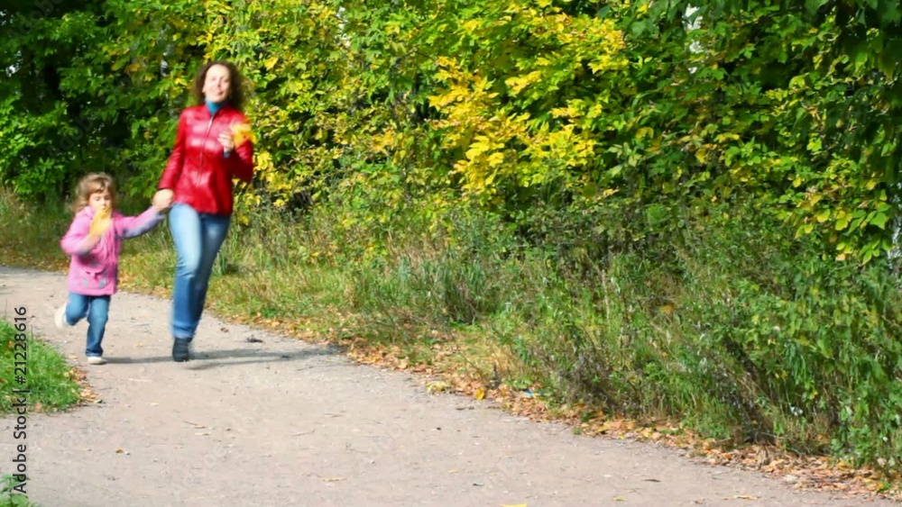 young woman with little girl running in autumn park, to camera young woman with little girl running in autumn park, to camera