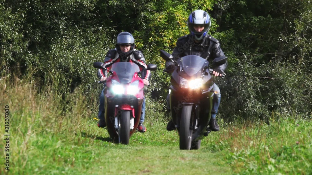 Two bikers on motorcycles goes forward on footpath in park Two bikers on motorcycles goes forward on footpath in park